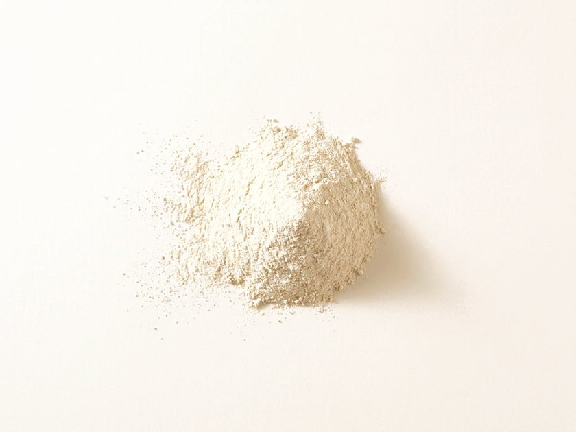 A small pile of pale cream-coloured collagen powder on a warm cream surface.