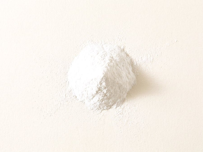 A small pile of fine white biotin powder on a warm cream surface.